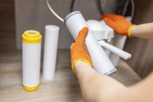 A professional water system technician holds up a canister to repair a water system