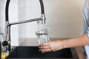 Woman filling drinking glass with tap water on the kitchen. 