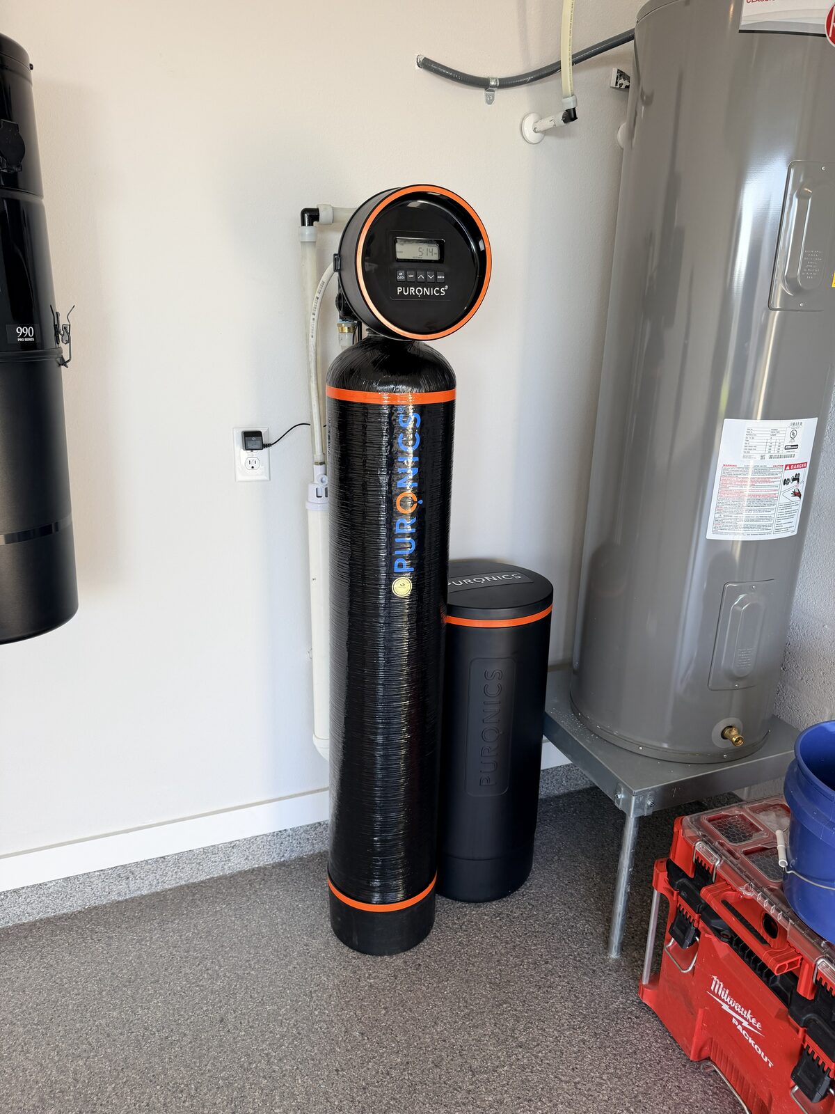 Puronics whole-home water softener in a garage next to a water heater