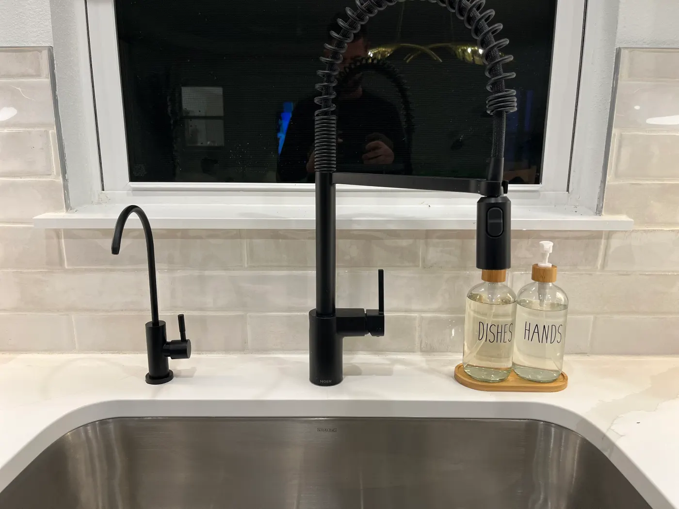 Matte black dedicated reverse osmosis drinking water faucet installed beside a matte black main kitchen faucet on a white quartz counter by Hydrology Water Solutions