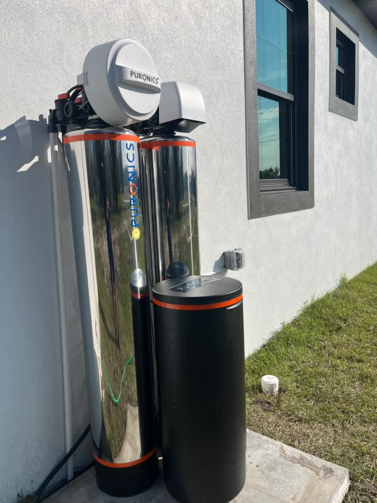 Twin stainless Puronics whole-home softener and filter with brine tank installed outside a new Suncoast home by Hydrology Water Solutions